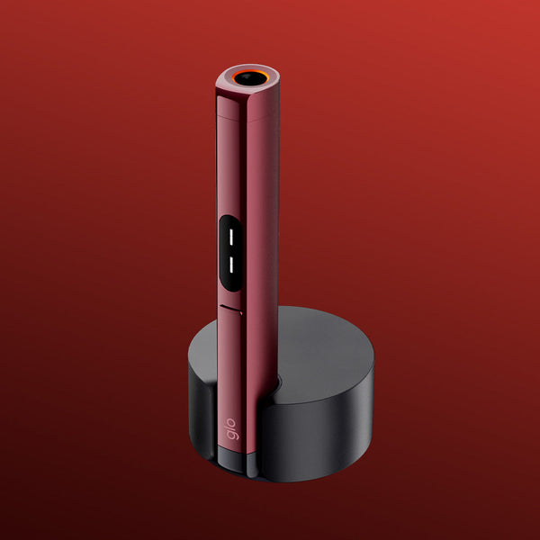 A sleek, red HILO Plus Pen with a circular tip stands upright in the glo™ HILO Plus Charging Dock, set against a gradient red background.