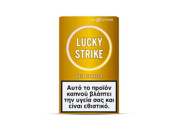 A yellow and gold pack of Lucky Strike Gold Tobacco cigarettes displays a Greek health warning label about the harmful and addictive effects of smoking. The tobacco offers nutty and creamy flavor notes.